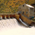 A pixelated static image shows a brown vehicle with a white roof on a light-colored surface, surrounded by blurred green and brown background elements.