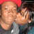 Two people pose closely together; one wears a red head covering and dark shirt, the other has long hair and a light gray top. The image shows subtle pixel changes across frames.