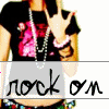 A person wearing a black shirt with pink heart design and white beaded necklace, making a hand gesture with fingers extended, with repeated text overlay.