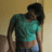 Pixelated figure in teal crop top and dark pants leaning against a wall with head bowed.