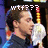 Pixelated image of a person with brown hair wearing a white shirt, holding a microphone with red and yellow stripes, and having white text above the head.