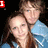 Two people in blue denim jackets pose closely together against a black background with text labels changing above them.