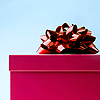 A static image of a bright pink gift box with a large red and white striped bow on top against a light blue background.
