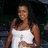 A pixelated image of a person in a white sleeveless top with dark hair, standing against a dark background.