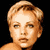 Pixelated static image of a person's face with light brown hair and neutral expression against black background.