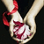 Pixelated image of a light-colored rabbit-like figure with red accents, holding a white object against dark background.
