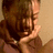A person with brown hair and a light-colored top holds their hand near their face in two showing slight movement