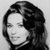 Black-and-white pixelated static image of a person's face with long hair, displayed on a gray background.