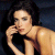 Static pixelated image of a person with dark hair wearing a black top, posed against a dark background with visible skin tones and lighting effects.
