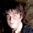 Pixelated static image of a person's face with light brown hair and dark background, rendered in low-resolution 256x256 pixels.