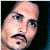 Pixelated close-up of a person's face with light skin tone, dark eyes, and a mustache, set against a dark background.