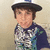 Pixelated image of a person wearing a dark wide-brimmed hat and a patterned shirt with blue, white, and green tones against a light beige background.