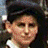 Pixelated close-up of a person's face with dark hair, light skin, and a neutral expression against a dark background.