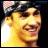 Pixelated close-up of a person's face with dark hair, yellow-toned skin, and a wide open mouth showing teeth, set against a dark background.