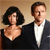 Static 50x50 pixel buddy icon featuring two people in formal attire against a beige background, with visible pixelation and dithering effects.