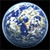 Pixelated circular image of a blue and white globe with visible landmasses and cloud patterns against a black background.