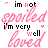 Animated text-based icon with pink and black lettering on white background, displaying phrases like "im not spoiled" and "i'm very well loved" in varying arrangements.