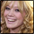 Pixelated image of a smiling person with curly blonde hair, split into four quadrants with black and gray backgrounds.