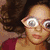 A pixelated collage of three distinct portraits: a person with curly brown hair and red glasses, another blowing pink bubble gum, and a third smiling in dark clothing.