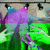 Animated green and purple figure with blue accents under stage lights, performing a motion sequence.