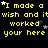 Yellow pixelated text on black background repeats 'I made a wish and it worked your here' with white and gray stars scattered across the frame.