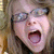 A person with light brown hair and glasses appears in a of four , mouth open in a shout across all