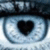 A pixelated close-up of a stylized eye with a black heart-shaped pupil, set against a light blue and white gradient background.