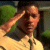 Pixelated image of a person with light skin and dark hair wearing a light-colored shirt, positioned against a green and dark background.