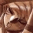 Pixelated static image of a character's face with closed eyes and dark hair, rendered in brown and beige tones on a solid background.
