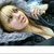A pixelated image of a person with light brown hair lying down, wearing a gray hooded garment and dark clothing.