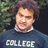 Pixelated image of a person with short brown hair wearing a dark blue shirt with white text reading "COLLEGE" against a blurred green and dark background.