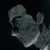 Pixelated grayscale image of a stylized animal figure with rounded head and body, dark eyes, and a light-colored underbelly against a black background.