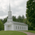 Pixelated image of a white church with a tall steeple, surrounded by green trees and grass under a cloudy sky.