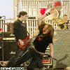 Animated sequence showing a band performing with guitarists and drummers in various poses, ending with text overlays.