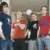 Group of five people standing together with one person holding a white object, next to large bold text reading 'McFLY' on the right side.