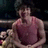 Pixelated image of a person in a sleeveless top with a blurred background and indistinct foreground elements.