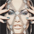 A pixelated static image shows a person with light skin holding two small objects near their face, set against a dark background.