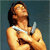 Pixelated static image of a person with dark hair wearing a white strap top, holding a cigarette near their mouth against a solid blue background.