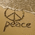 A beach scene with a peace symbol drawn in sand, waves washing over it, and the word 'peace' written below.