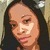 Pixelated close-up of a person with long dark hair, light skin tone, and visible facial features including eyes, nose, mouth, and eyebrows.