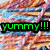 Green text 'yummy!!!' on black background with red heart symbol over abstract colorful patterned backdrop.