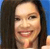 Pixelated close-up of a person with long dark hair against a blue background, showing a smiling expression with visible teeth.