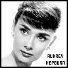 Black-and-white portrait of a woman with short dark hair styled in a vintage cut, wearing earrings and a light-colored garment.