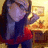 Pixelated image of a person with long dark hair wearing a dark blue top with red accents, holding a glowing object against a warm-toned background.