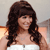 A pixelated image of a person with long dark hair wearing a white sleeveless top against a light background with orange accents.