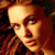 Pixelated close-up of a person with reddish-brown hair and warm lighting against dark background, rendered in low-resolution 256x256 pixels.