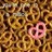A static pixelated image with a brown and gold patterned background and a pink circular symbol with dark inner sections in the lower right.