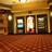 A pixelated interior view of a movie theater with wooden paneling, illuminated doorways, and a brown floor.