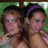Two people with dark hair pose closely together against a green and white pixelated background, one wearing a purple headband.