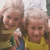 Two children in yellow shirts pose together, one with a hand on the other's shoulder against a light background.